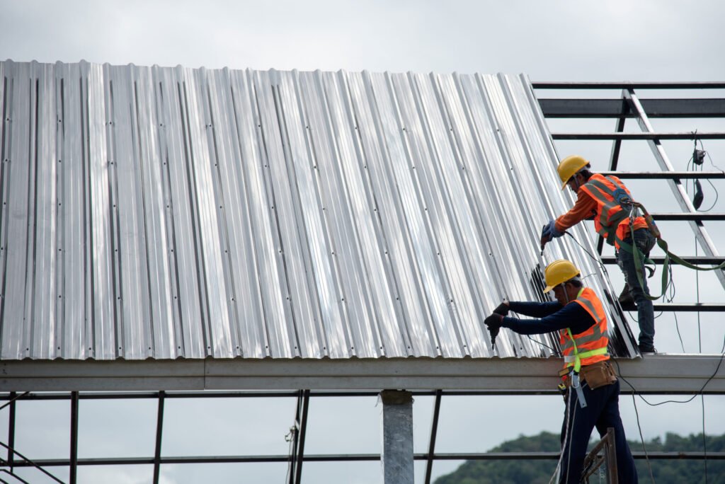 Roofing contractors with fall protection, roof safety harness, ropes are  finishing to install asphalt roof shingles on the gable house roof. Roofing  construction. Stock Photo