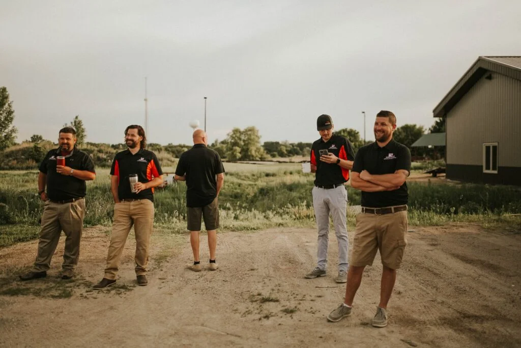 Five Heritage Exteriors staff stand outside smiling and holding mugs